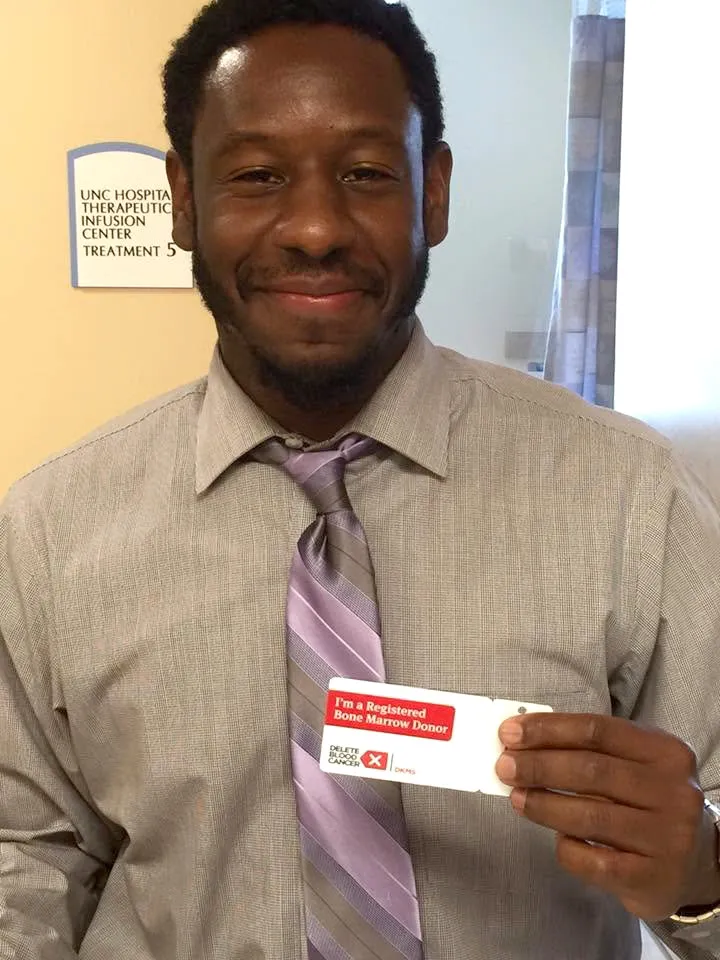 Michael Desronvil holds his bone marrow donor registration card.