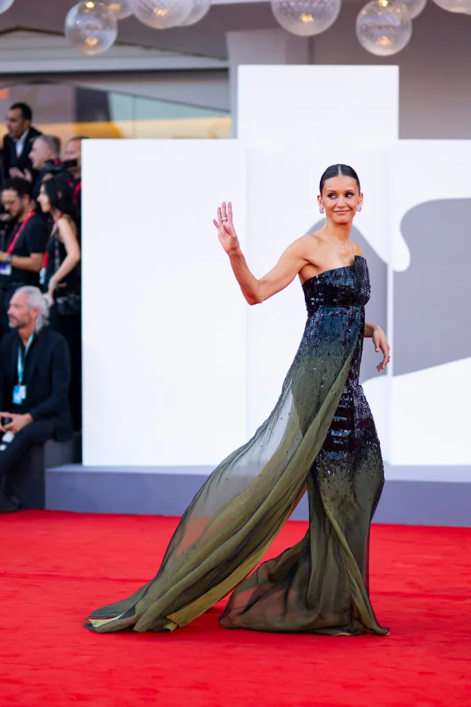 Nina Dobrev on the red carpet, waving.