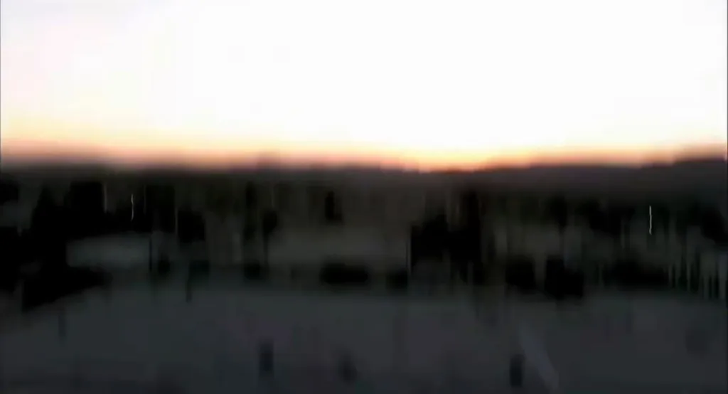 Video still from inside a KNBC news helicopter during its final moments before crashing, showing the ground accelerating rapidly below under a fading sunset.