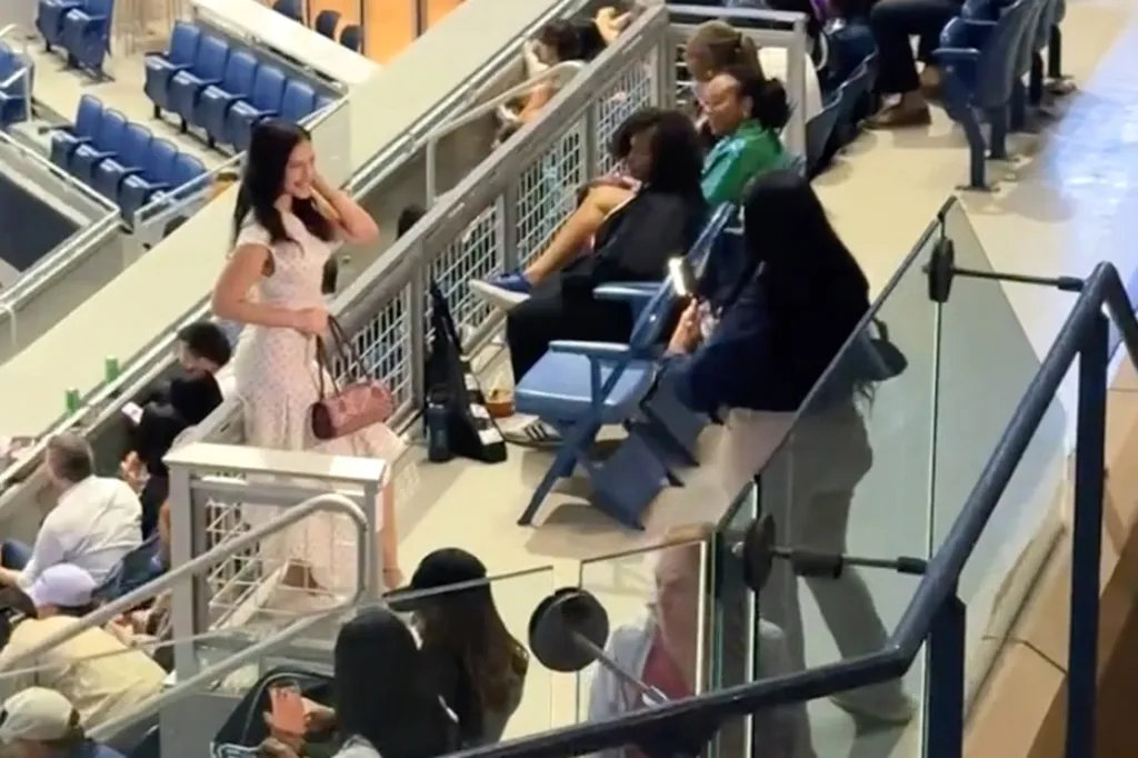 A woman holding a very bright light to capture content during Naomi Osaka's match.
