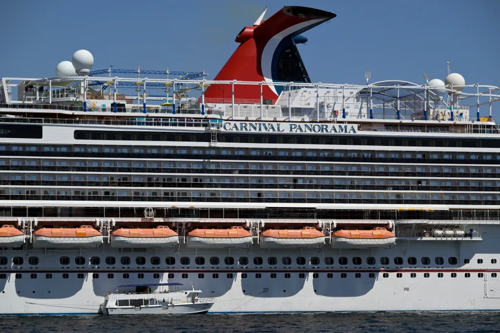 The Carnival Panorama cruise ship with multiple decks and a distinctive red, white, and blue funnel.