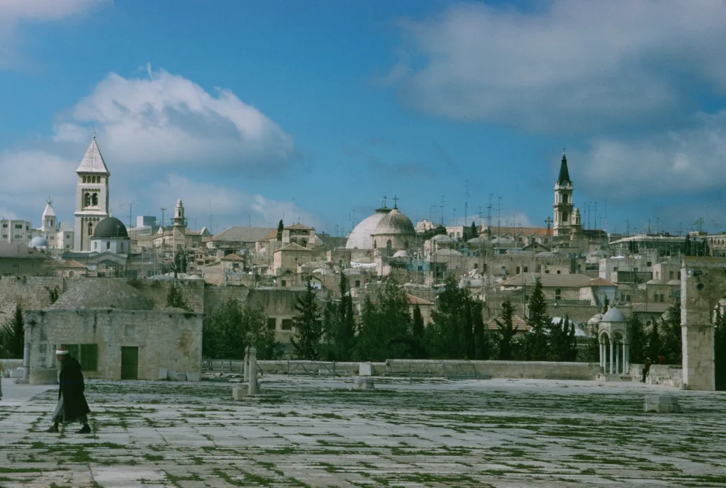 View from the Dome of the Rock of the Old City of Jerusalem, with a man walking in the foreground.