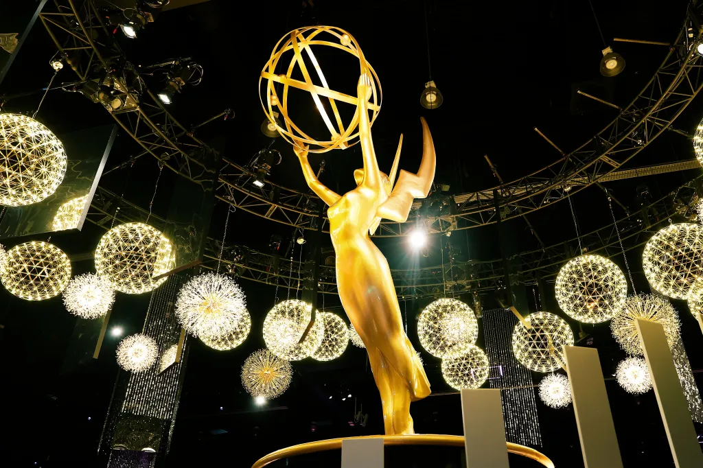 Emmy statue illuminated by lights and surrounded by decorative spheres.