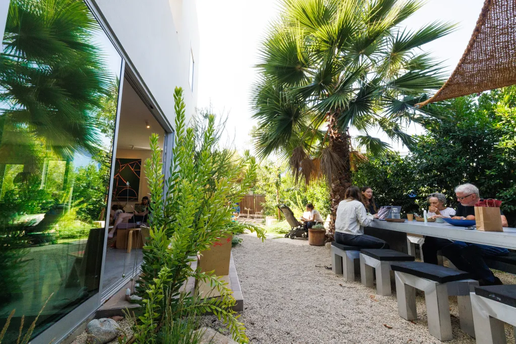 Visitors at GRANADA in Los Angeles gather at an outdoor long table and indoors in a communal setting.
