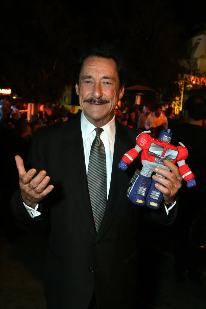Voice actor Peter Cullen, known as the voice of Optimus Prime, holding an Optimus Prime plush toy.