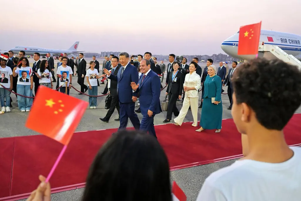 Chinese President Xi Jinping and Egyptian President Abdel Fattah El-Sisi walk on a red carpet with their wives and others.