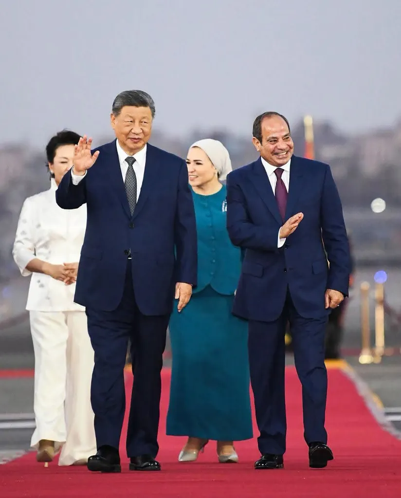 Chinese President Xi Jinping and Egyptian President Abdel Fattah El-Sisi, accompanied by their wives, walk on a red carpet.