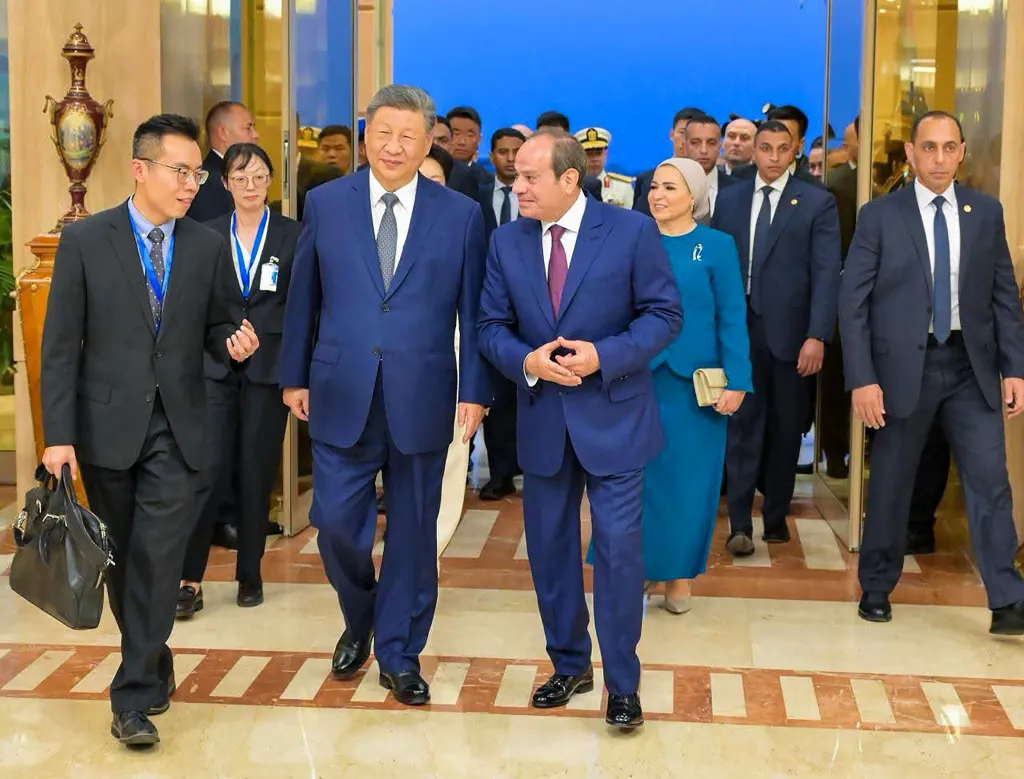 Chinese President Xi Jinping and Egyptian President Abdel Fattah El-Sisi walk through an airport terminal with their wives and an entourage.