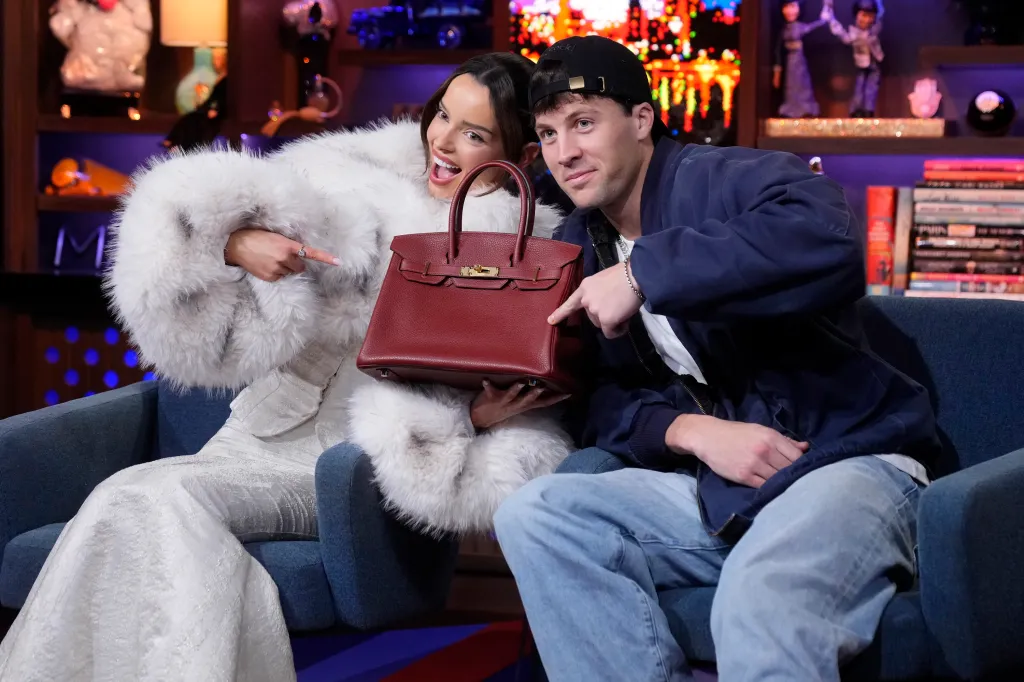 Maura Higgins and Rob Rausch pose, pointing at a red handbag.