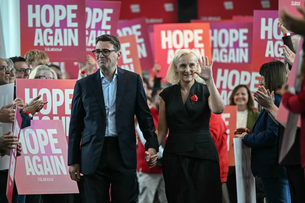 Britain's Prime Minister Andy Burnham and his wife Marie-France van Heel are welcomed upon arrival ahead of his speech at the annual Labour Party conference.