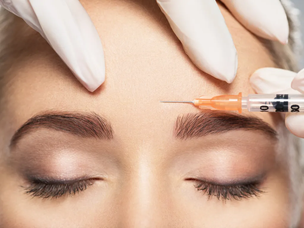 Woman receiving a Botox injection in her forehead.