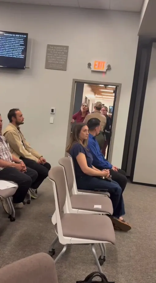 A woman being escorted out of a Tulare County Board of Supervisors meeting.