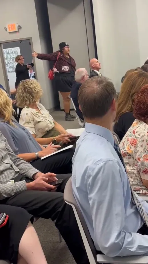 A woman being escorted out of a Tulare County Board of Supervisors meeting.