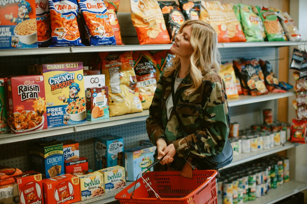 A woman shops for drinks and snacks in a small convenience store.