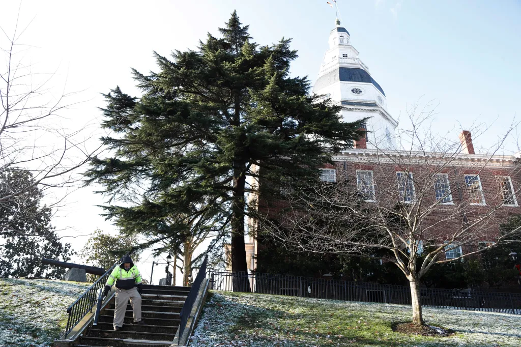 A worker blowing leaves and snow off steps outside the Maryland Statehouse.