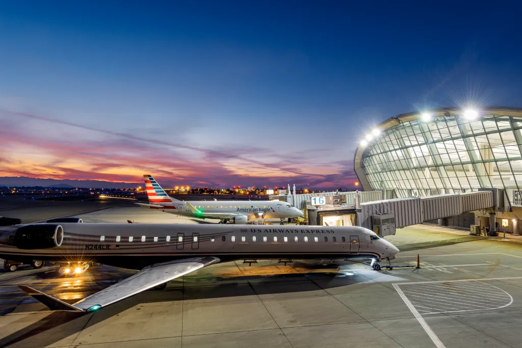 Fresno Yosemite International Airport at dusk with two planes parked at the terminal gates.