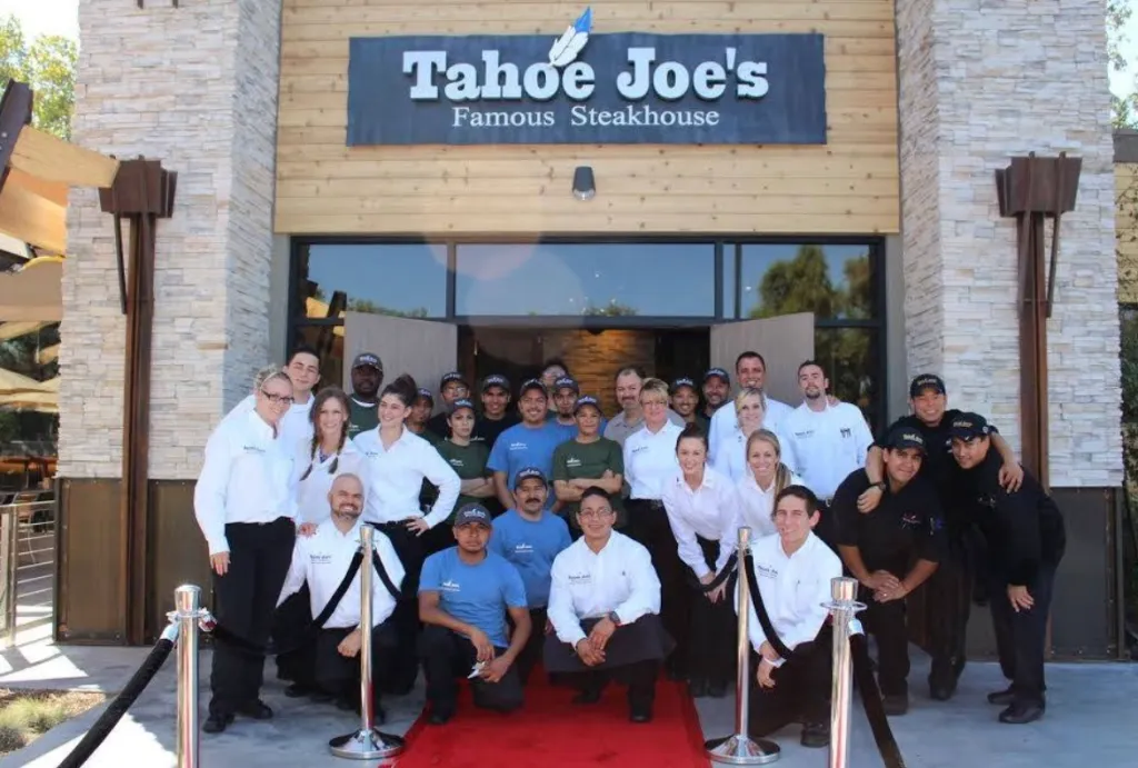 Staff of Tahoe Joe's Famous Steakhouse gathered on a red carpet in front of the restaurant.