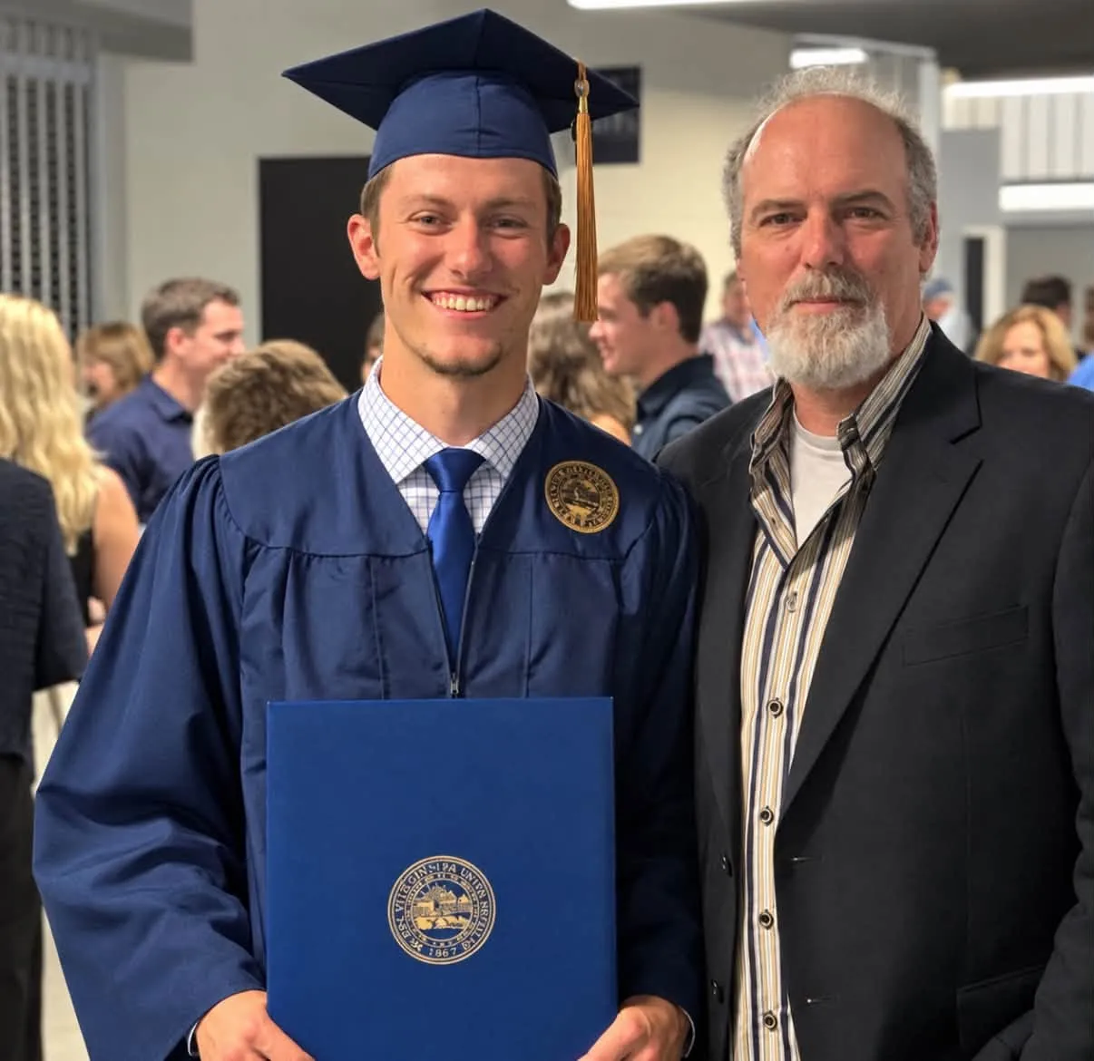 Zachary Morris, in a graduation cap and gown, smiles next to his father, Brian Duckworth, at his graduation.