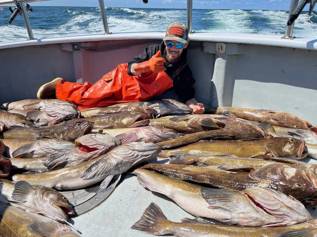 Todd Meadows giving a thumbs-up while lying on a boat filled with fish.