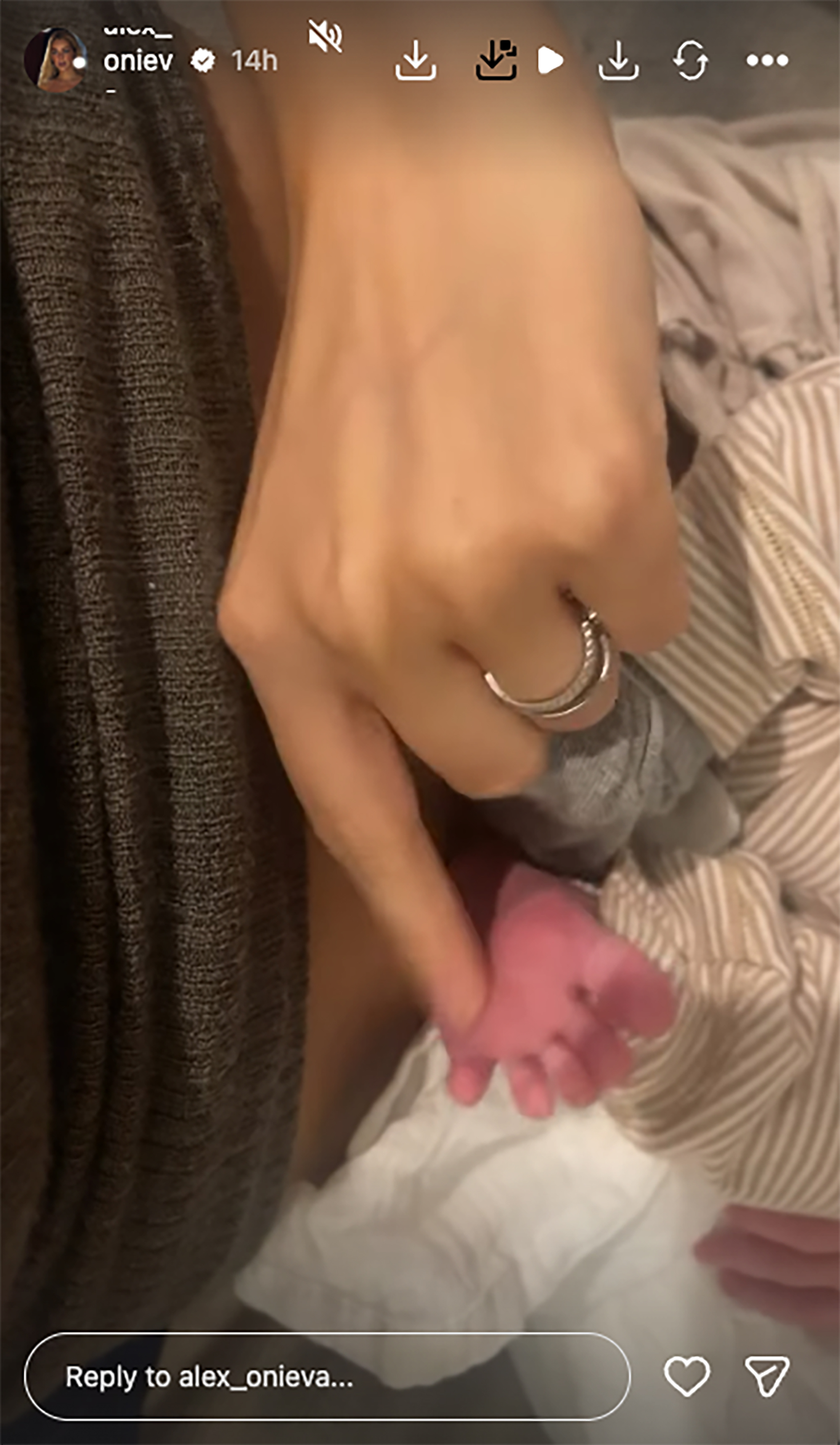 A close-up of a person's hand with a ring holding a newborn baby's tiny foot.