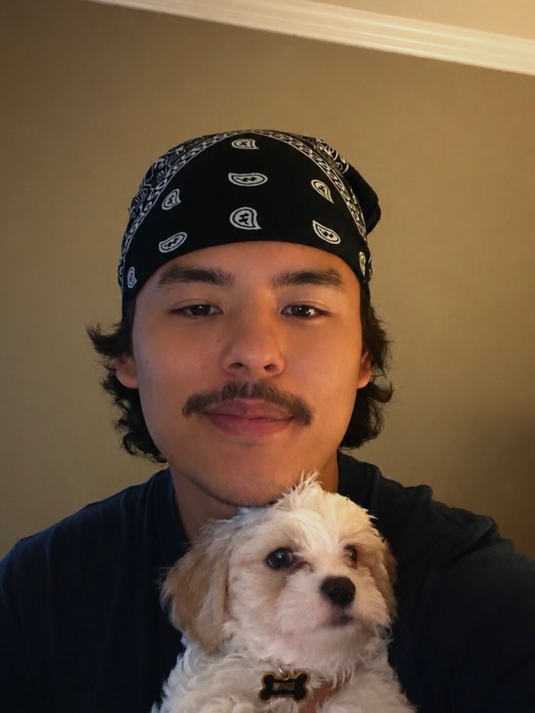 Collin Gosselin smiling, wearing a bandana and holding a small white dog.