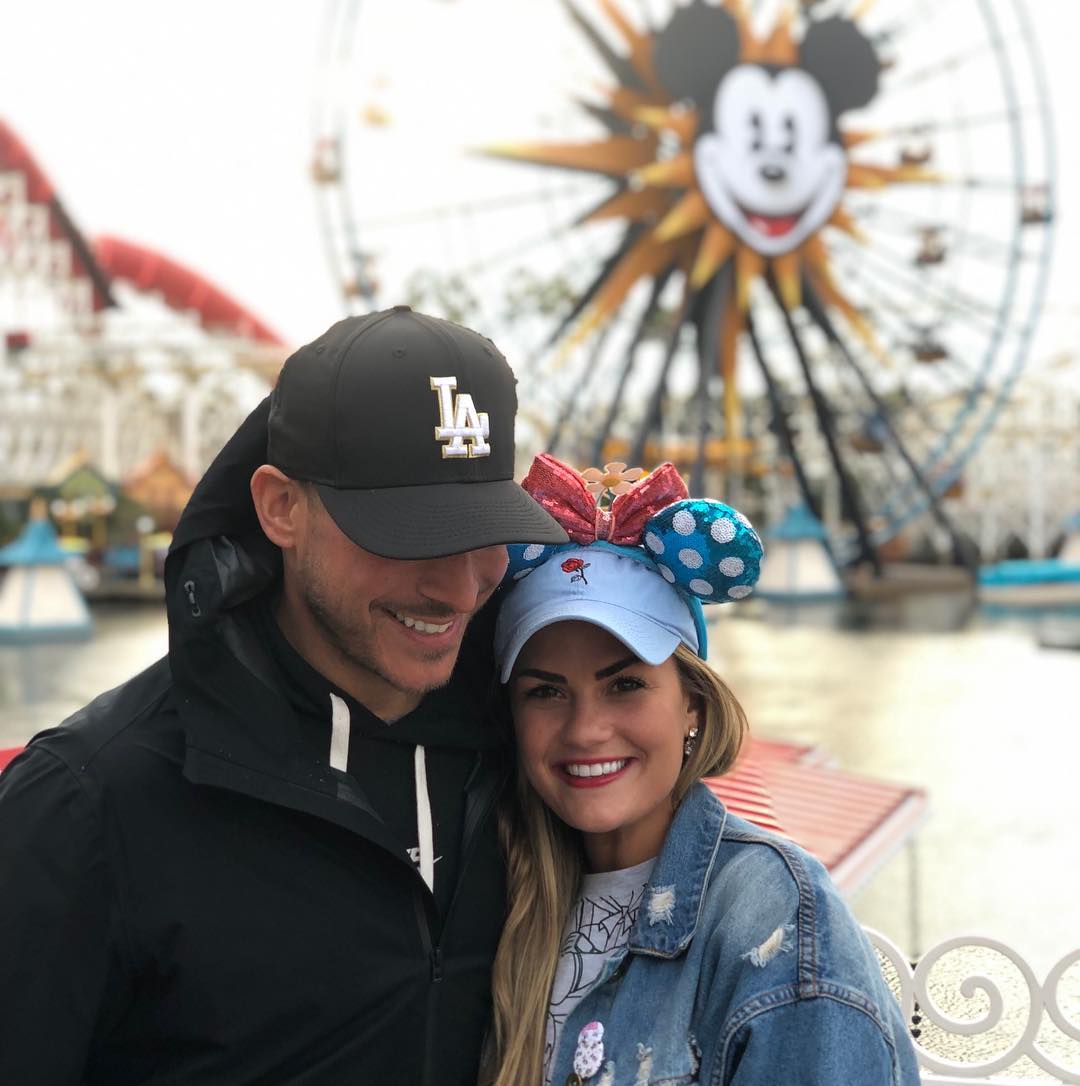 Jax Taylor and Brittany Cartwright smiling in front of a Ferris wheel with a Mickey Mouse face.