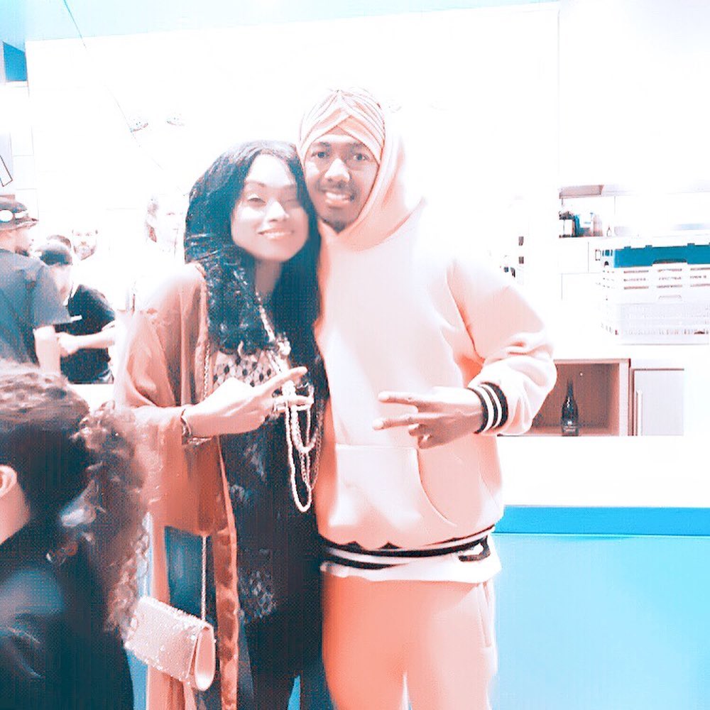 Christy Knowings posing with Nick Cannon, both making peace signs.