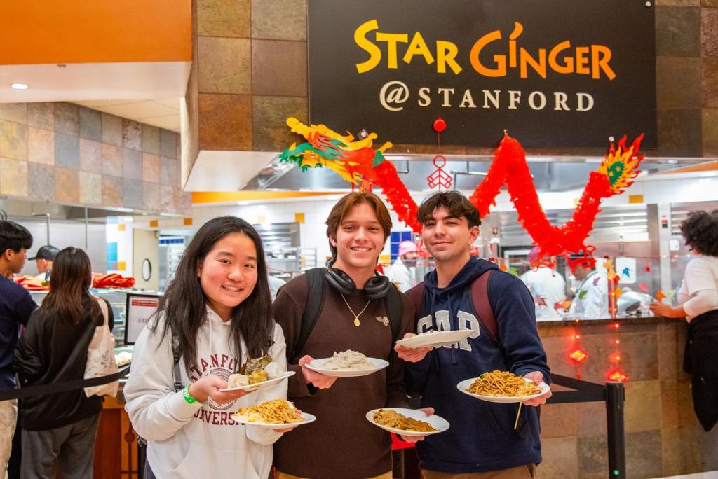 Three Stanford students holding plates of food under a 