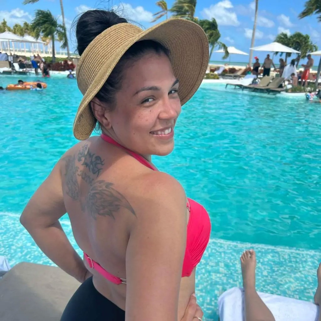 Amber Eggers in a red bikini top and sun hat by a pool.