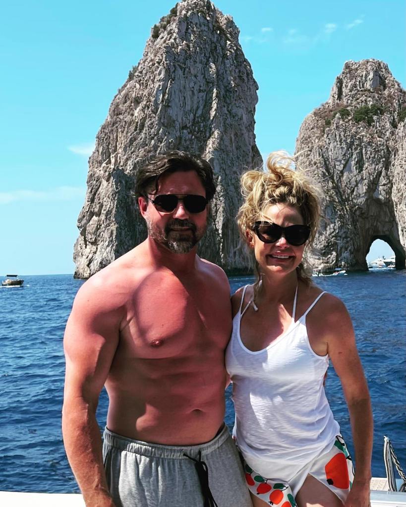 Denise Richards and Aaron Phypers posing on a boat in front of Faraglioni, Italy.
