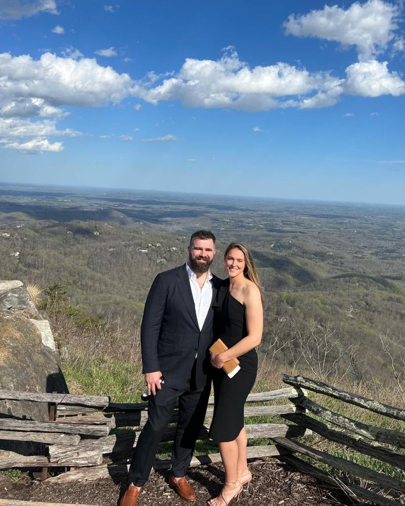 Jason and Kylie Kelce posing together on a mountain overlook.