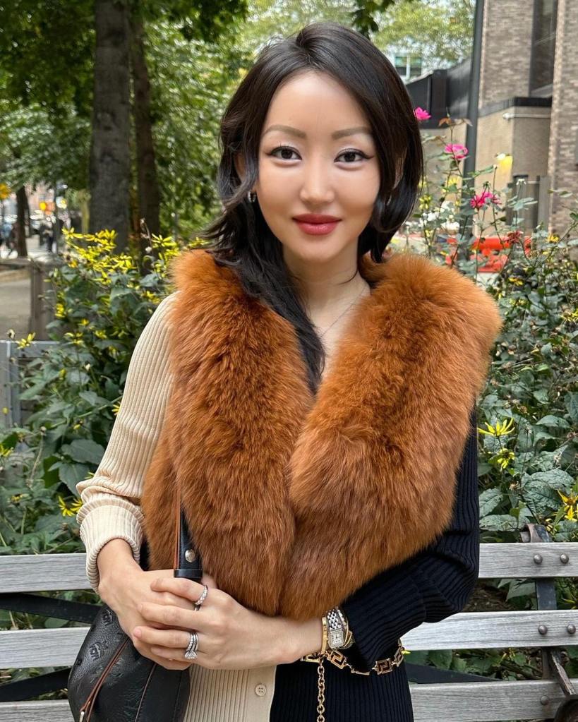 Yeonmi Park standing outdoors, wearing a fur collar and holding a black purse.