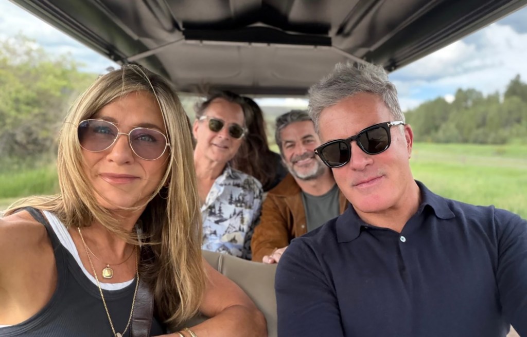 Jennifer Aniston and three men take a selfie from inside a golf cart.