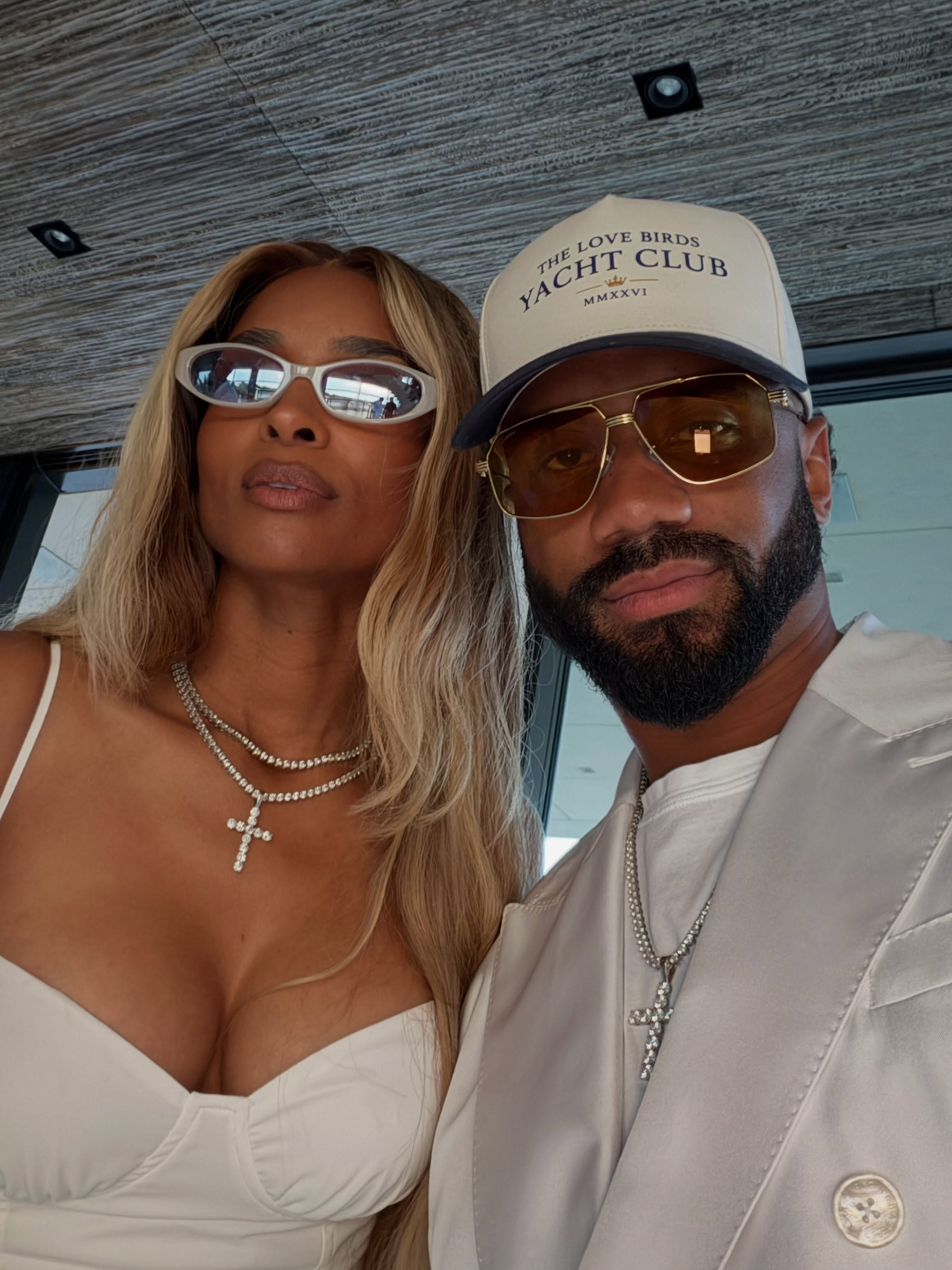 Ciara and Russell Wilson in white outfits and sunglasses.