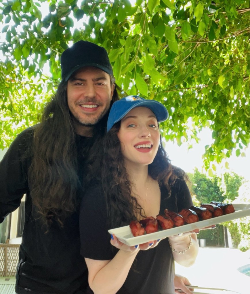 Kat Dennings and Andrew W.K. smiling, with Dennings holding a platter of grilled meat.