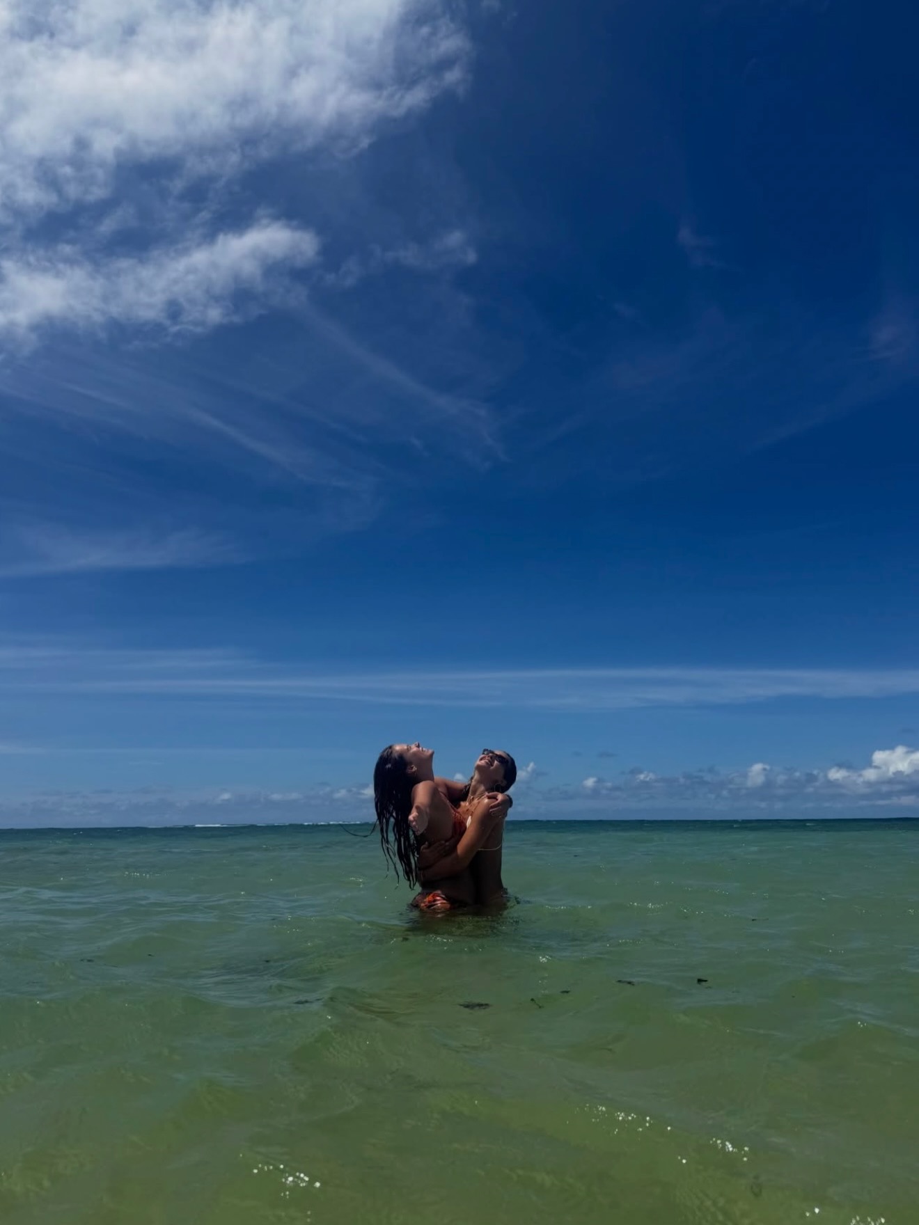 Jessica Alba with her daughter Honor in the ocean, both looking up and smiling.