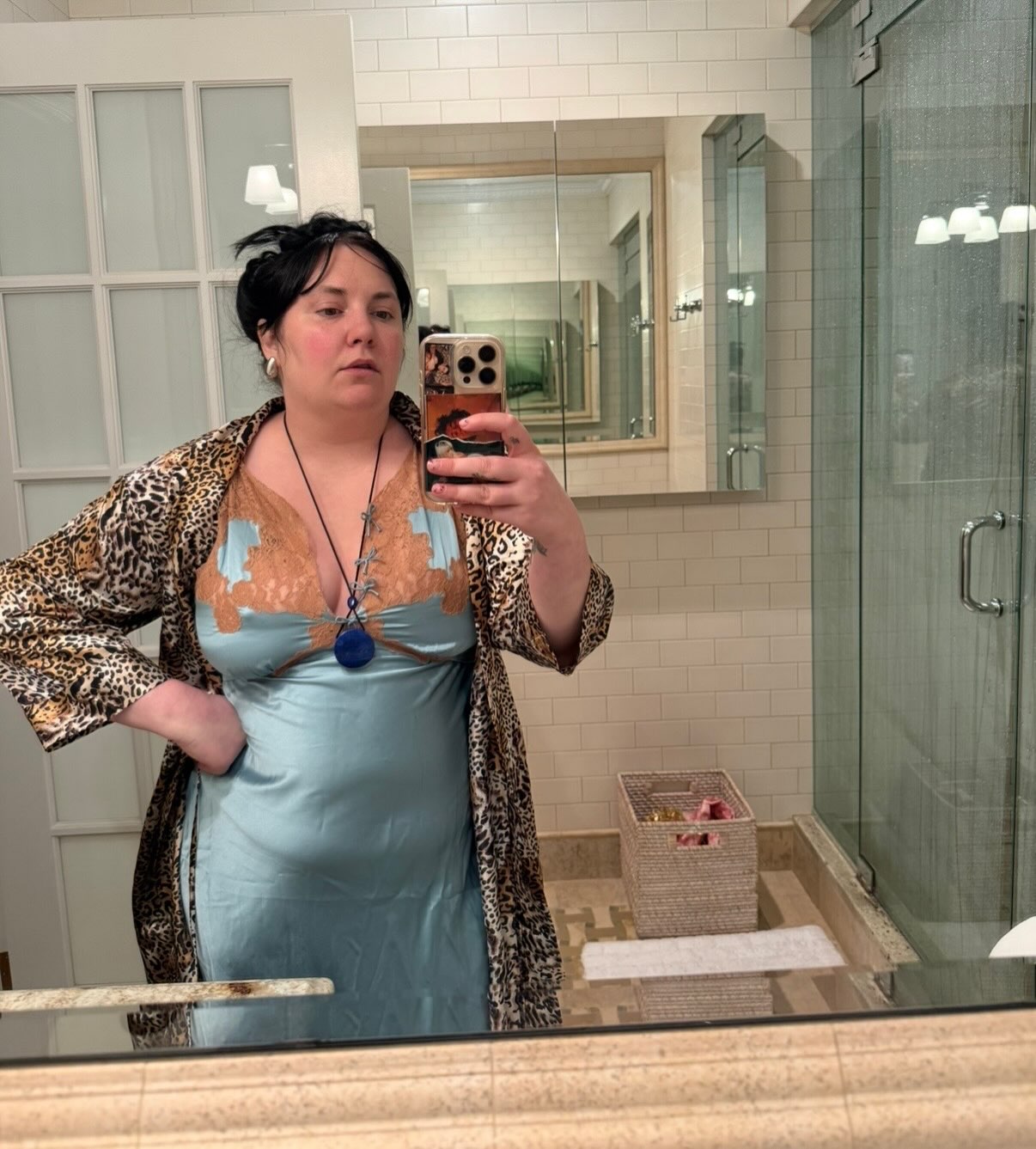 Lena Dunham takes a mirror selfie wearing a blue and peach slip dress and leopard print robe.
