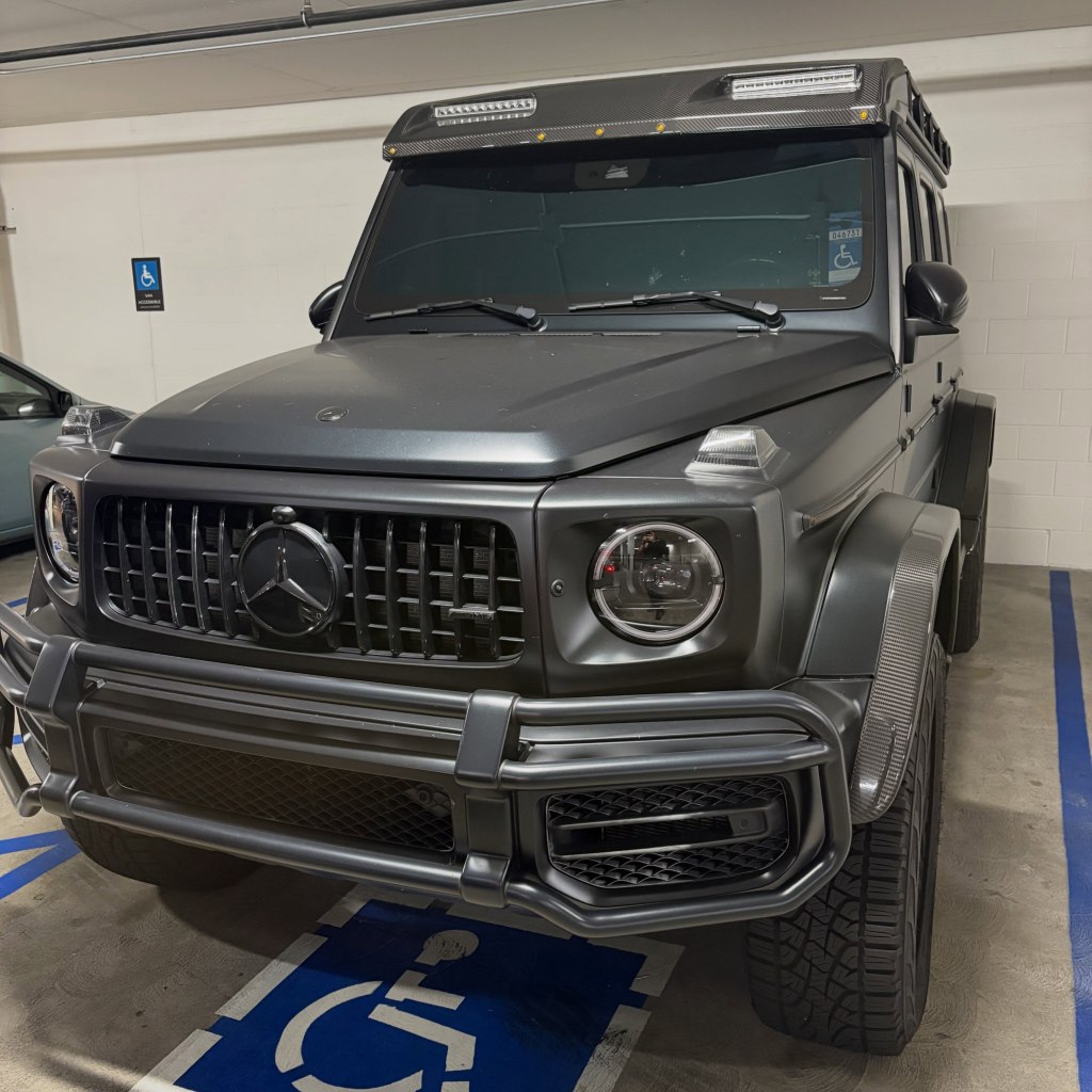 Gray luxury vehicle parked illegally in a handicapped spot.