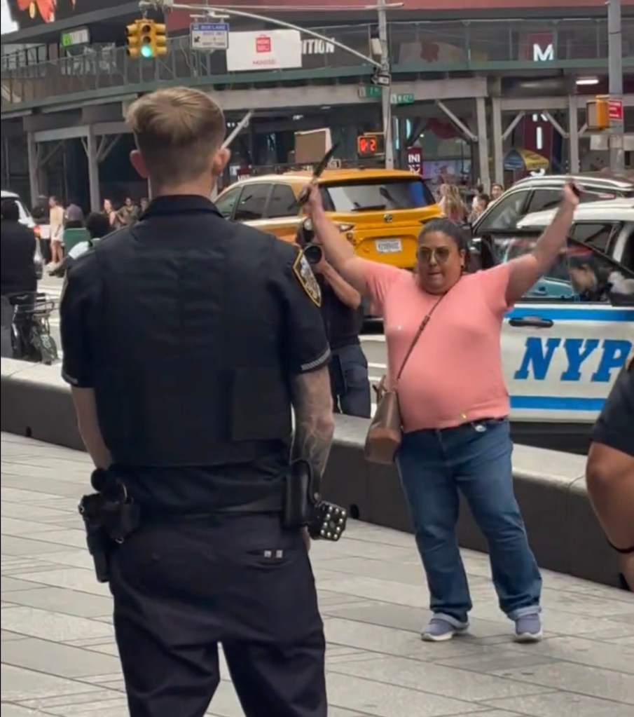 A woman in Times Square holding a knife, facing a police officer.