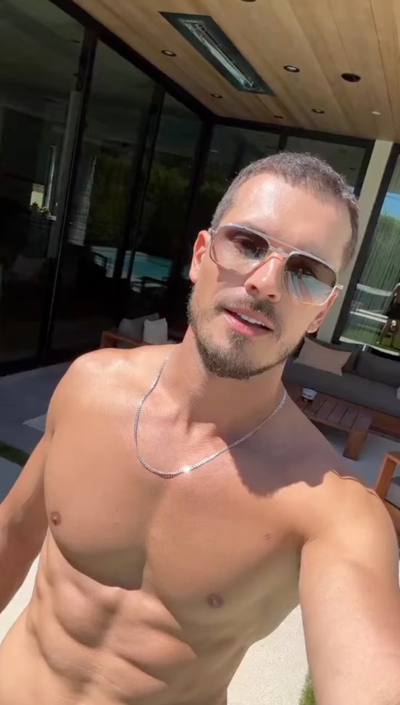 Gleb Savchenko posing shirtless outdoors wearing sunglasses and a silver chain.