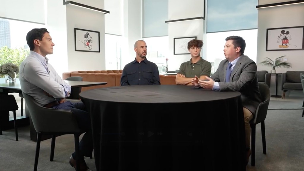 Four men are seated around a round black table in an office setting, with Will Reeve on the far left.