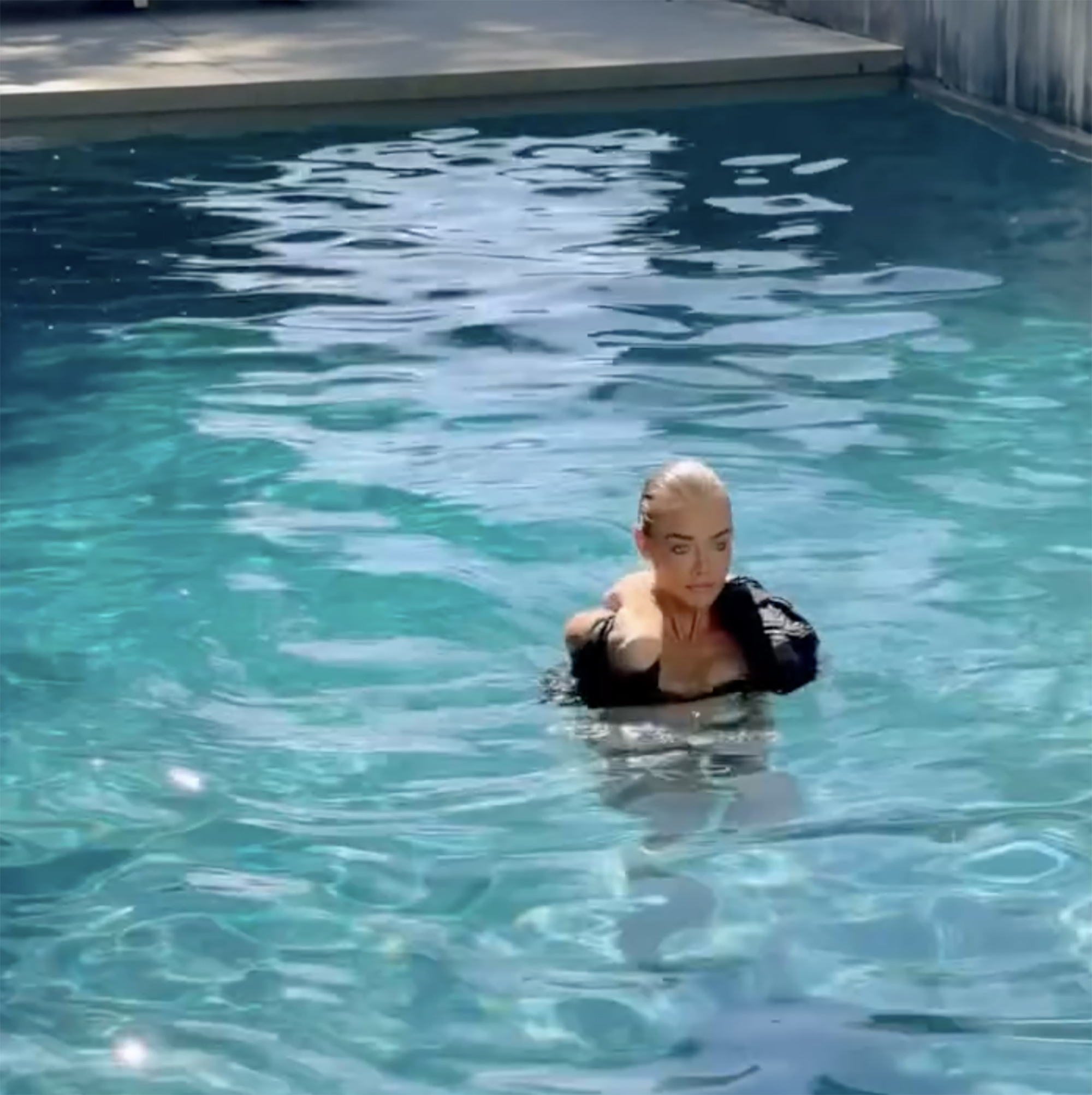 Denise Richards emerges from a pool, recreating her iconic 