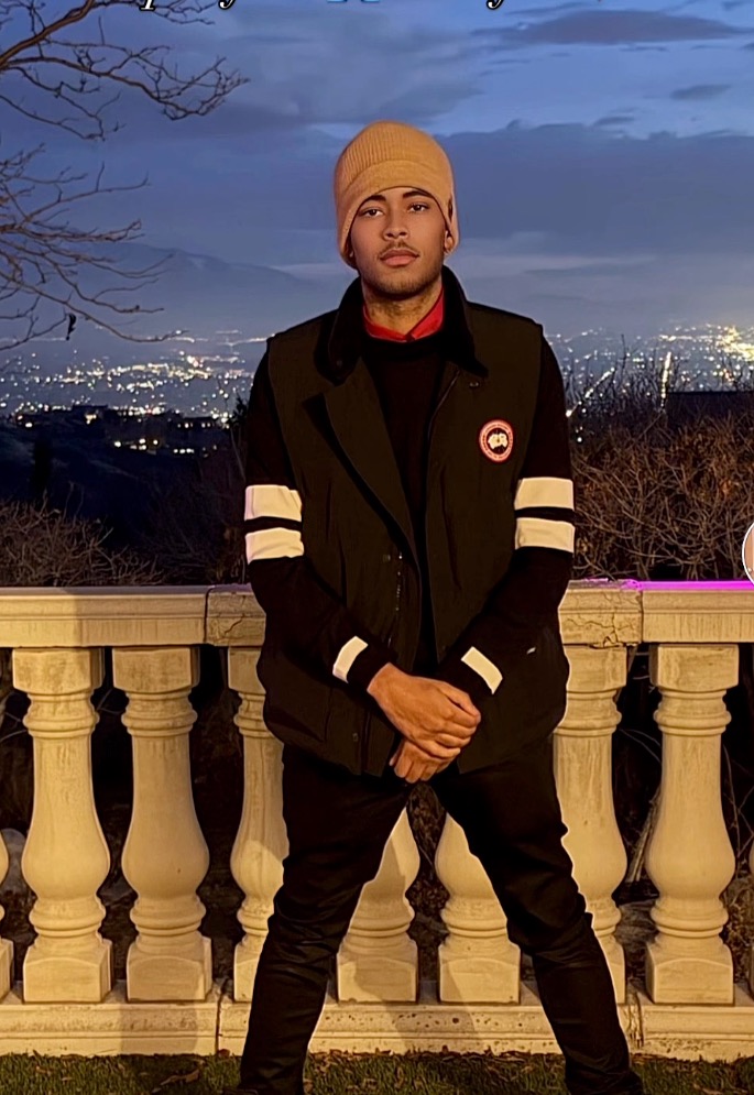 Mary Cosby's son posing in front of a city lights backdrop.