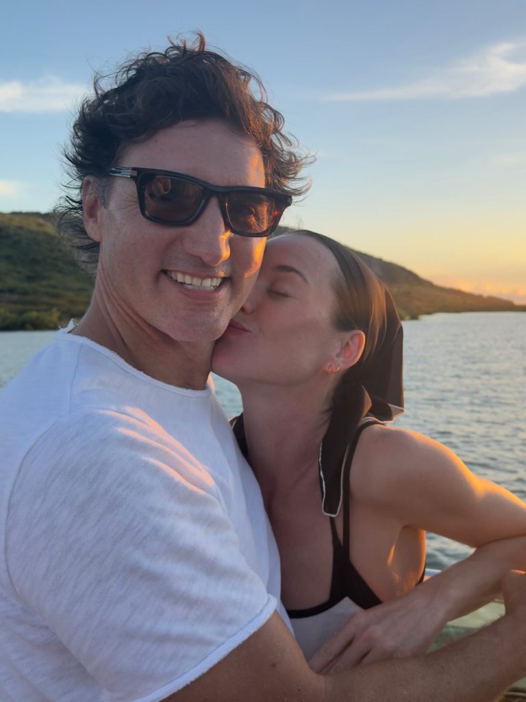 Katy Perry kissing Justin Trudeau on the cheek during sunset on the water.