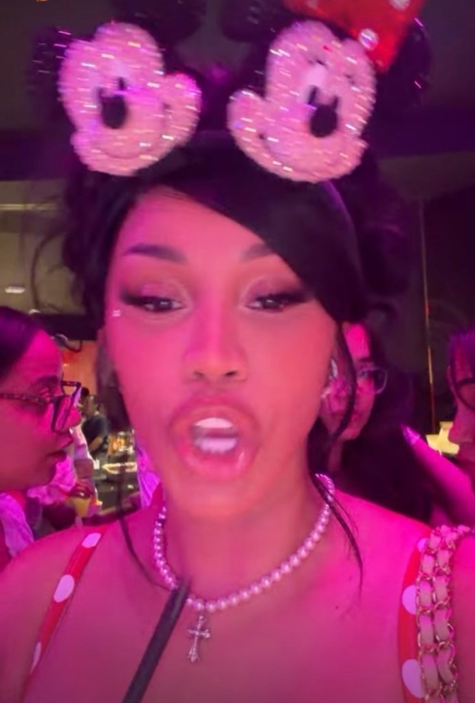Cardi B wearing Minnie Mouse ears and a pearl necklace with a cross pendant.