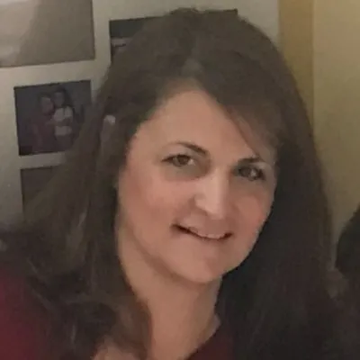 A smiling woman with long brown hair and a dark red top.
