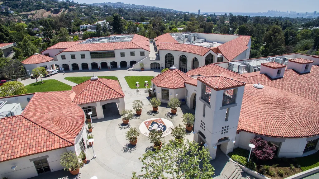 Aerial view of Harvard-Westlake School campus, showing buildings with red-tiled roofs, courtyards, and lush greenery.