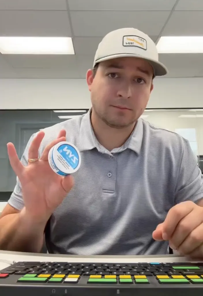 Nolan Borgersen in an office holding a container of Zyn nicotine pouches.