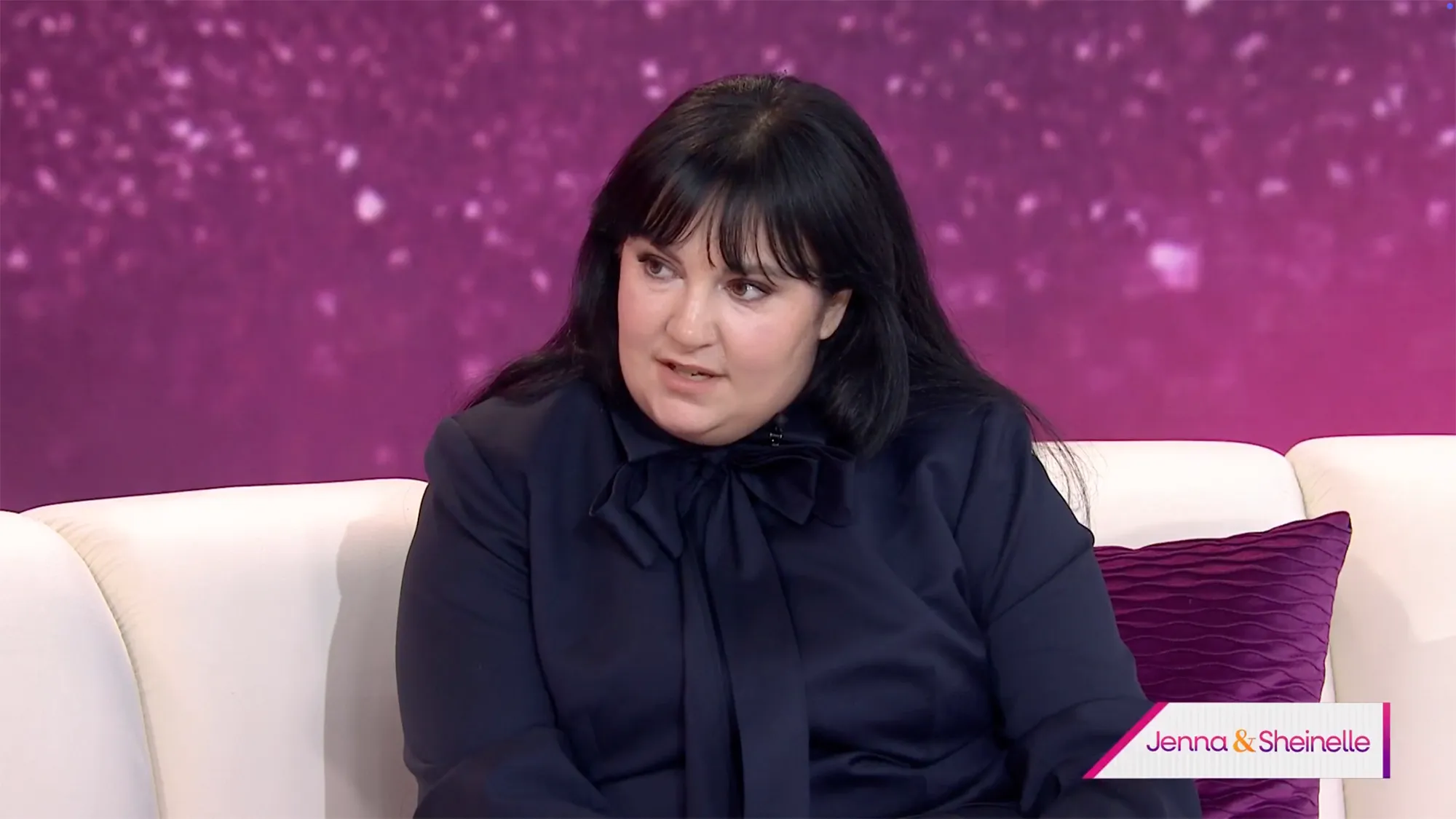 Lena Dunham sits on a white couch.