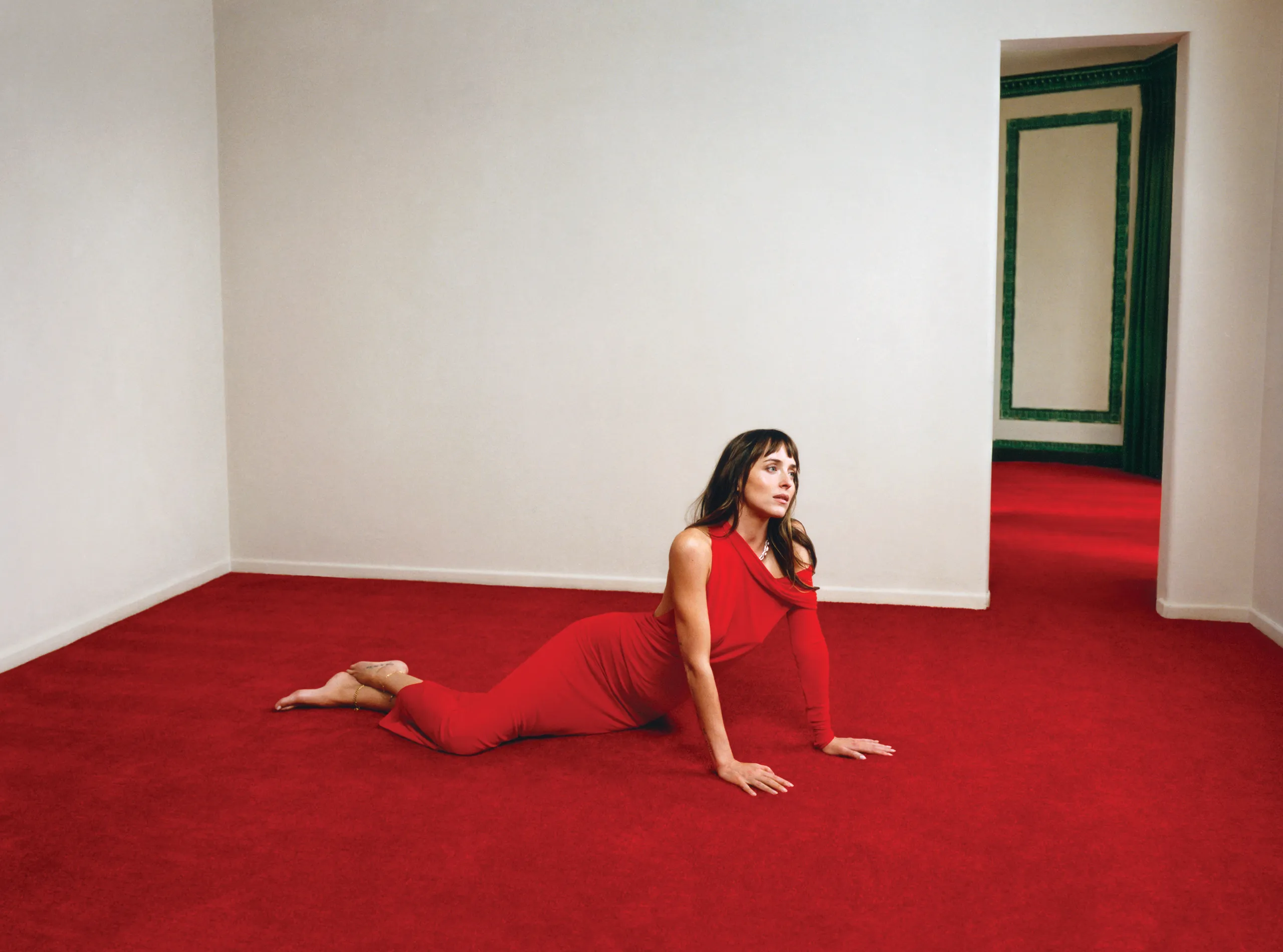 Dakota Johnson on a red carpet in a red dress.